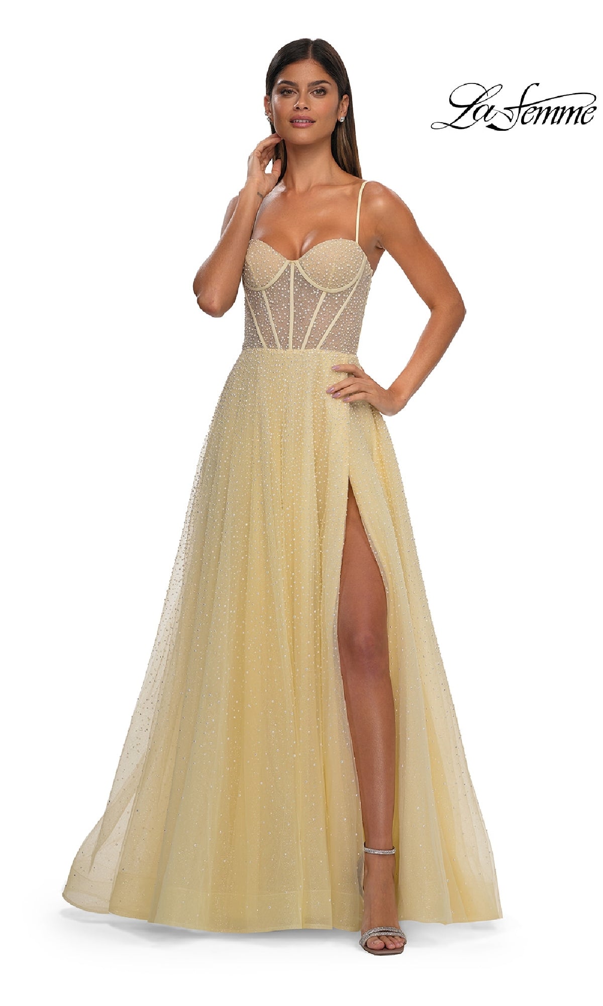 A woman wearing the Pearl Classic Long Prom Dress: La Femme 32644, a light yellow A-line evening gown with a sheer corset bodice, spaghetti straps, high slit, floor-length skirt, and subtle sparkle.